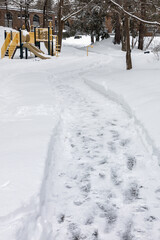 Pedestrian pathway covered with snow in residential park in winter