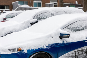 Parked cars covered with snow in residential area after winter snowfall
