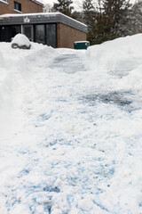 Pathway with salt and melting snow. Road to houses in residential neighborhood in winter snowy season