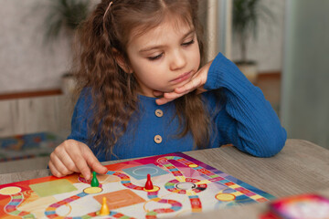 Portrait of little girl 5 years old with interest looks at board game