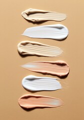 Smears of skincare and foundation creams in beige, white, and peach tones on a nude background