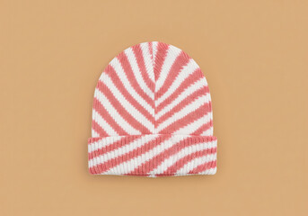 Pink and white striped knit beanie on a beige background. Top view shot for winter fashion and cold weather accessories.