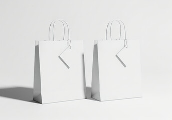 Two empty white paper shopping bags with labels on them, standing on a white surface. Minimal product mockup for brand and logo presentation.