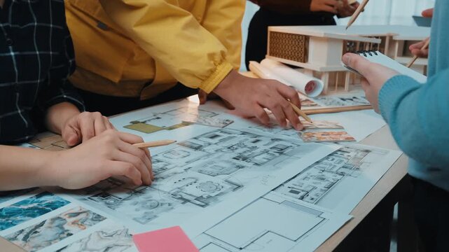 Group of diverse individuals engaged in a collaborative architectural design session, working on plans and sketches, emphasizing creativity and teamwork in the process. SACTR