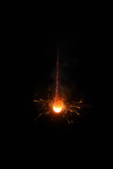 Glowing firework sparkler creating bright sparks against darkness  
