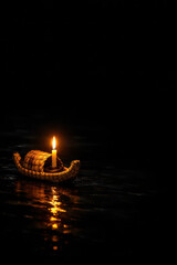 Floating candle on water illuminated against dark background  