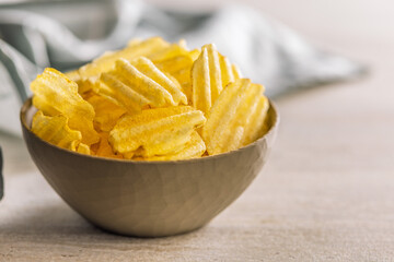 Wavy potato chips in bowl on kitchen table.