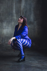 Elegant mature woman in a blue suit and tights. Gorgeous beautiful attractive plus size young woman with long hair. Body positive concept. Happy smiling single female