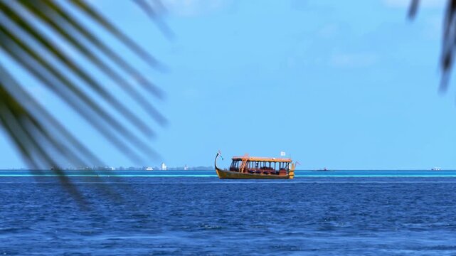 Traditional wooden boat sailing on blue ocean in Maldives