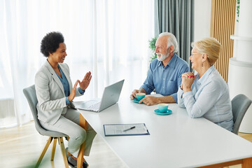 Senior couple having a meeting with an agent using a laptop computer , businesswoman, salesperson...