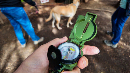 A Compass being used on the trail to find direction using the magnetic field of the earth with a needle that points at magnetic north with a bezel to set the directions