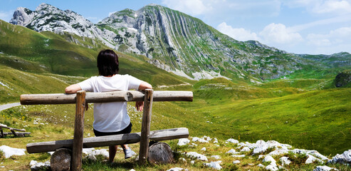 Girl sitting on wooden bench in mountains of Montenegro. Young girl resting in National park Durmitor with scenic nature view