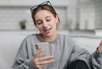 Smiling Young Woman Chatting Via Video Call While Sitting On A Sofa In A Light Room
