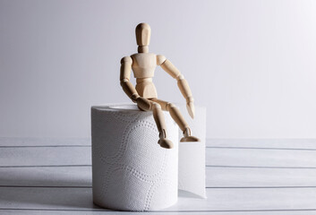 Wooden figure sit on a roll of toilet paper. Concept of the problem with digestion
