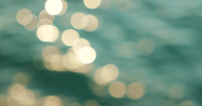 Glittering sun reflections create abstract bokeh pattern on ocean ripples