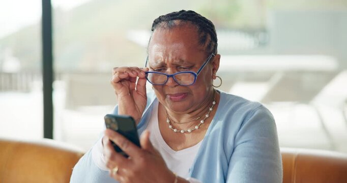 Elderly woman, glasses and phone for reading, scam message or fake news on sofa in living room. Annoyed, notification and senior african person with technology, online fraud and doubt in home