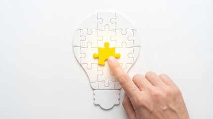 Creative lightbulb puzzle concept with hand placing final yellow piece, business innovation and solution symbol, problem solving strategy, teamwork inspiration, completing the idea.