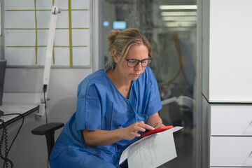 Medical professional using smartphone and paperwork in clinic