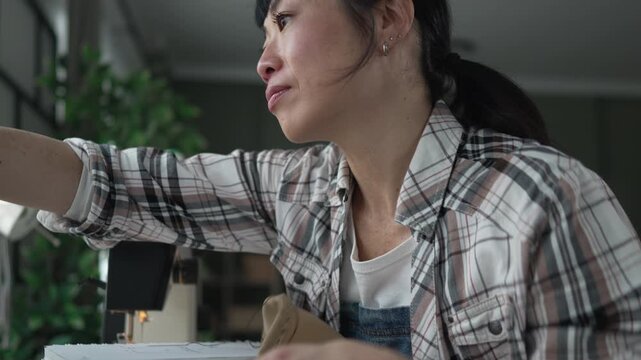 Tailor woman pinning sketch on pegboard for new fashion design