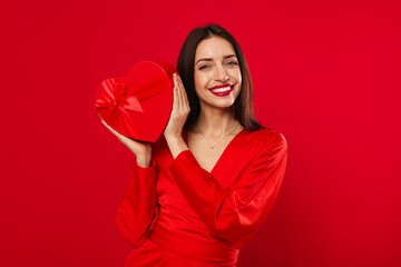 St. Valentine's Day. Beautiful woman with gift on red background