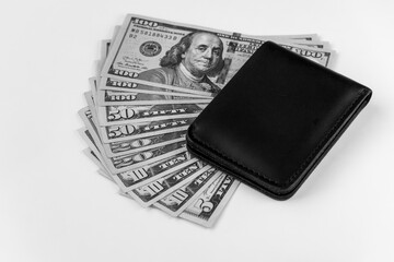 Dollar banknote USA of different denominations folded like a fan and man black wallet in blur. White background, isolated.