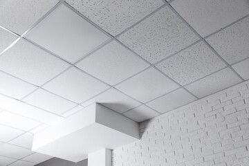 Tiled ceiling with lighting and ventilation indoors, low angle view