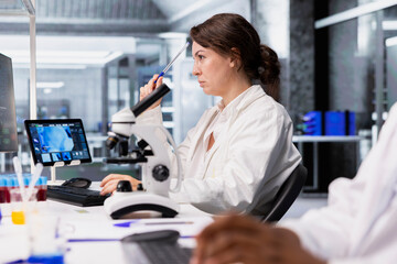 Lab technician looking at 3D molecular model visualization on computer monitor. Woman using bioengineering software on PC in medical lab displaying DNA data, doing brainstorming