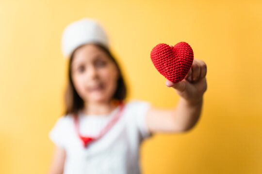 Child plays doctor holding a heart symbol.