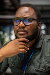 Obraz premium Black general manager envisioning rational solution and scratching his chin, works after hours at desk. Man engaging in critical thinking, evaluating each option for a different perspective.