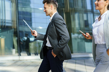 Business professionals walk while using mobile devices