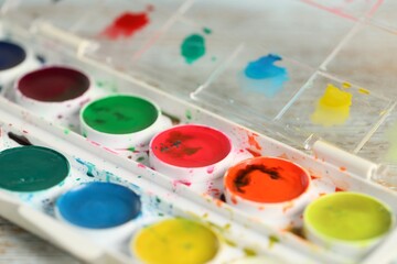 Palette with watercolor paints on table, closeup