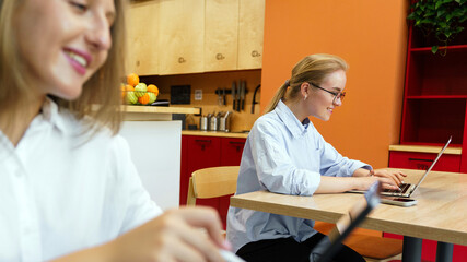 Two women working on laptops in a modern workspace