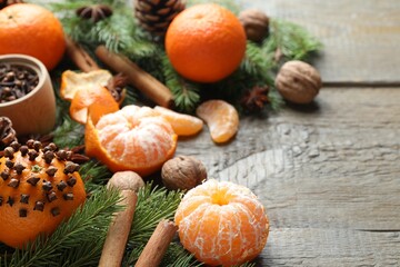 Ripe tangerines, spices, walnuts, fir tree branches and cone on wooden table, closeup. Space for text