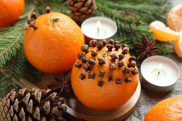 Ripe tangerines, spices, cones, fir tree branches and burning candles on table, closeup