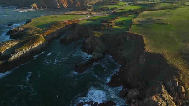 Aerial view toward rocky coastline with parked vehicles, northern Spain