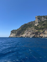 Naklejka premium Sunlit Beach with Majestic Cliffs and Deep Blue Sea