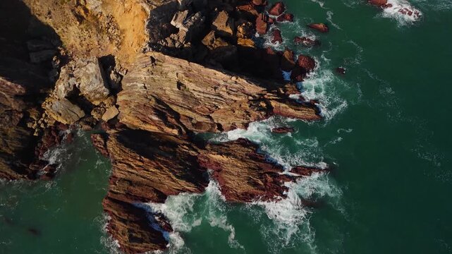 Dark aerial view of rocky coastline with crashing waves, northern Spain