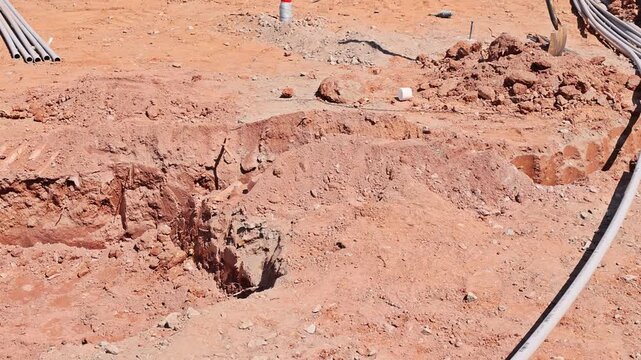 Excavation work reveals deep trenches in dry soil, with utility pipes laid out indicating work waste water pipes installation