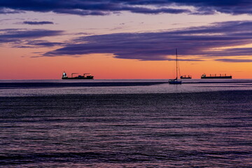 sagome di navi da trasporto e barca a vela al tramonto viste dal lungomare di Salerno (Campania , Italia)