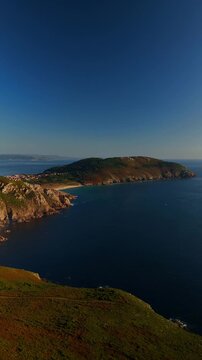 Aerial landscape view toward coast and distant city with beach and ocean, Fisterra, Spain, vertical video