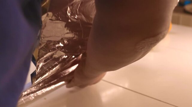 Close-up of hands seasoning and placing a whole raw goose on a baking tray with herbs and oranges, then sliding it into the oven. Traditional festive cooking, holiday meal preparation, home kitchen pr