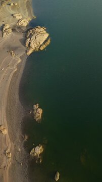 Aerial high angle view of rocky shore and lake water, Almendra Reservoir, Spain, vertical video