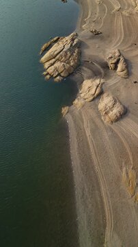 Aerial high angle view of lake and rocky shore with flying bird, Almendra Reservoir, Spain, vertical video