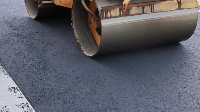 October 14 2025 New York USA Heavy roller compacts freshly laid asphalt on road under construction during