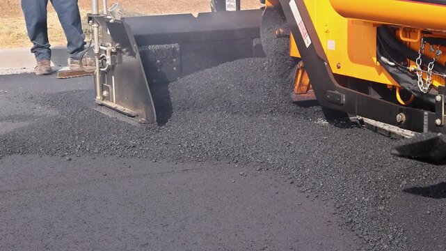 Worker uses shovel to fill pothole with asphalt in residential neighborhood during road works
