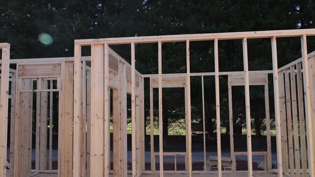 Workers are building wooden house frame, trusses roof supports studs joist overhead.