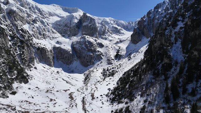 Snowy mountain peak with rocky cliffs and winter landscape aerial