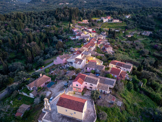 Fototapeta premium Aerial view of a picturesque village with colorful houses nestled among lush trees on a hillside.