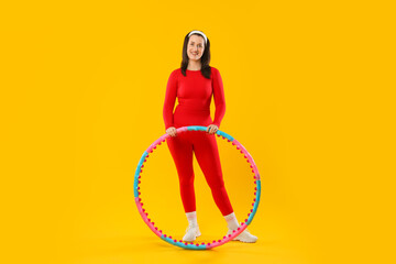 Happy woman with hula hoop on yellow background