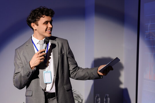 Male business speaker with tablet computer conducting seminar near projector screen in office - Powered by Adobe